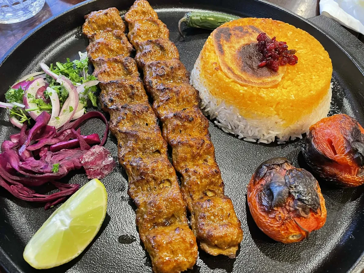 Persian kebab with saffron rice, grilled tomatoes, and salad