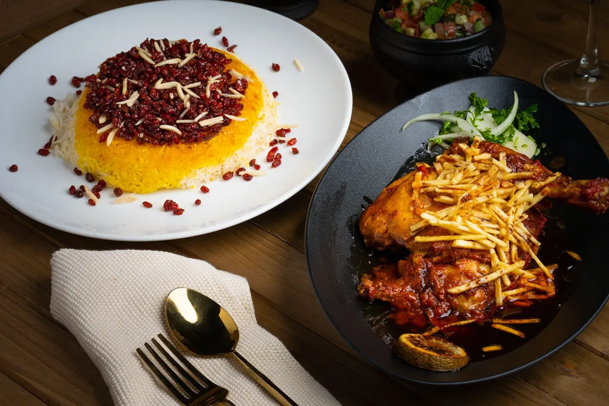 Two plates of Persian food on a wooden table